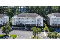 Three-story condo building with white balconies, ample parking, and lush landscaping at 698 Riverwalk Dr. # 304, Myrtle Beach, SC 29579