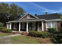 Charming brick home featuring a welcoming front porch with classic columns and manicured landscaping at 124 Orange St., Georgetown, SC 29440