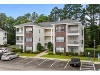 Exterior of condo building with brick accents, white siding, and multiple balconies overlooking a landscaped courtyard at 1302 River Oak Dr. # 4B, Myrtle Beach, SC 29579