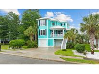 Charming two-story home with a vibrant turquoise exterior, a white roof, and a well-manicured lawn at 17 Trigger Fish Ln., Murrells Inlet, SC 29576