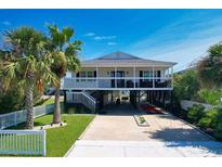 Inviting elevated beach house featuring a covered parking area and beautifully landscaped front yard at 312 35Th Ave. N, North Myrtle Beach, SC 29582