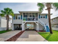 Charming elevated home featuring palm trees, a screened-in porch, and covered parking with stairs leading to the main level at 321 53Rd Ave. N, North Myrtle Beach, SC 29582