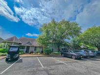 Gray condo building with ample parking, mature trees, and blue skies overhead at 323 Wendover Ct. # 10-A, Myrtle Beach, SC 29572