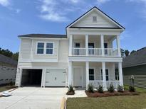 Charming two-story home with a double porch, attached garage, and well-maintained landscaping and a garage for two cars at 3338 Sw Wood Stork Dr., Ocean Isle Beach, NC 28469