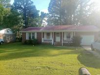 Charming brick home with a red metal roof, inviting porch, and a lush green front lawn at 3909 Mallard Circle, Myrtle Beach, SC 29579