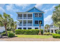Charming blue two-story home with double balconies and a beautifully landscaped front yard at 573 S Dunes Dr., Pawleys Island, SC 29585
