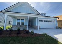 Charming light blue home featuring a two-car garage, covered porch and manicured lawn at 1005 Lady Bird Way, North Myrtle Beach, SC 29582