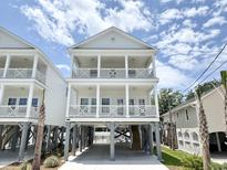 Beautiful elevated home with double porches, gray pilings, white wood railings, and attractive landscaping at 135A Sunset Dr., Murrells Inlet, SC 29576