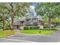 Charming condo featuring a well-maintained exterior with lush landscaping and mature trees providing shade and curb appeal at 213 Westleton Dr. # 16-D, Myrtle Beach, SC 29572