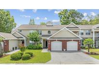 Charming exterior view of townhome showcasing manicured lawn, brick accents, and a two-car garage at 2150 Longwood Lakes Dr. # 2150, Myrtle Beach, SC 29579