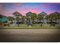 Charming colorful homes with white picket fences, palm trees, and stairs leading to covered porches at 22 Ocean Blvd. N, Surfside Beach, SC 29575