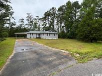 Exterior of home with large front yard, mature trees, long driveway and convenient carport at 321 Circle Heights Dr., Loris, SC 29569