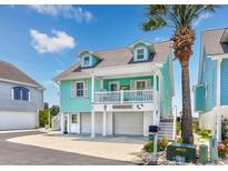 Charming two-story turquoise beach home with white trim, a balcony, and a lush palm tree in the front at 4534 Landing Rd., Little River, SC 29566
