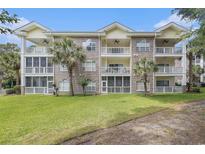 Three-story condo with brick facade, balconies, palm trees, and a well-maintained lawn at 4721 Hibiscus Dr. # 3-302, Little River, SC 29566