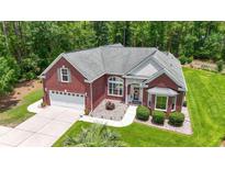 Aerial view of a charming red brick home featuring a well-manicured lawn and a two-car garage at 499 Trestle Way, Conway, SC 29526