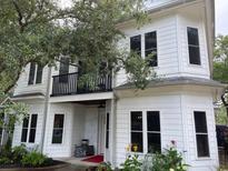 Charming white two-story home with balcony, black trim, and manicured landscaping at 514 Blockade Dr., Pawleys Island, SC 29585