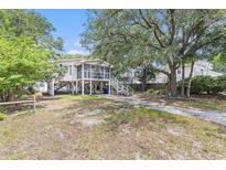 Charming stilt home featuring a screened porch, driveway, and lush surrounding trees at 910 N Dogwood Dr., Surfside Beach, SC 29575