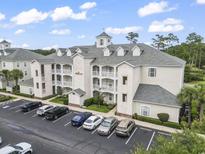 View of the condo with a manicured lawn, balconies, and ample parking space at 1009 World Tour Blvd. # 105, Myrtle Beach, SC 29579