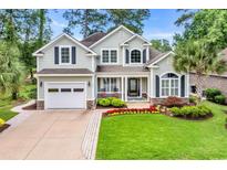 Charming two-story home with a well-manicured lawn, beautiful landscaping, and a welcoming front porch at 124 Turtle Creek Dr., Pawleys Island, SC 29585