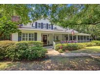 Charming home exterior featuring a welcoming porch, beautiful landscaping, and American flag decor at 3772 Brown Bark Ln., Murrells Inlet, SC 29576
