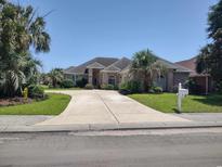 Charming brick home featuring a circular driveway and mature landscaping, including palm trees, on a sunny day at 413 Sea Vista Ln., North Myrtle Beach, SC 29582