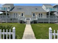Charming beach house featuring symmetrical design, white picket fence, and well-maintained lawn at 4806 S Ocean Blvd., Surfside Beach, SC 29575