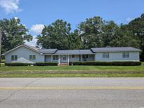 Charming single-story home features a well-manicured lawn, mature trees, and a welcoming front porch at 5370 Miracle Ln., Conway, SC 29526