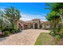 Stunning home featuring a paver driveway, tile roof, stone accents, and a well manicured lawn with palm trees at 9737 Catalonia Ct., Myrtle Beach, SC 29579