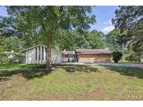 Charming home featuring a mix of brick and white siding, nestled among mature trees on a well-maintained lawn at 103 Wofford Ln., Conway, SC 29526