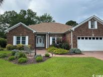 Charming brick home featuring a well-manicured lawn, bench seating, and a two-car garage at 105 Ashley River Rd., Myrtle Beach, SC 29588