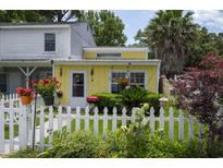 Charming yellow home featuring a white picket fence, lush garden, and vibrant flowers, creating a welcoming curb appeal at 12 Century St. # 12, Myrtle Beach, SC 29577