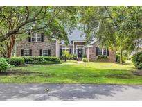 Charming brick home with lush green lawn, mature trees, and inviting front entrance at 139 Olde Canal Loop, Pawleys Island, SC 29585