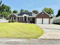 Charming brick home with a well-manicured lawn, solar panels, and attached two-car garage at 1421 Shoreline Dr., Myrtle Beach, SC 29577