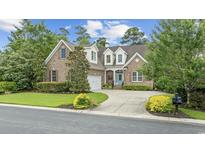 Charming brick home with manicured lawn, mature trees, and welcoming blue front door at 28 Grey Moss Rd., Murrells Inlet, SC 29576
