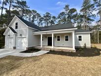 Charming single-story home with a covered front porch, manicured lawn, and attached two car garage at 33 Hope Ln., Pawleys Island, SC 29585