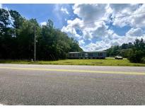 Charming single-story home features a gray exterior, lush lawn, and mature trees, creating a serene, private setting at 3353 Fries Bay Rd., Loris, SC 29569