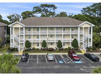 Three-story condo building with white railings, stairs, parking, and landscaping at 4261 Hibiscus Dr. # 4-104, Little River, SC 29566
