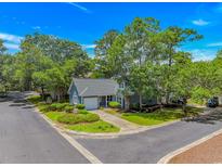 Charming blue home with lush landscaping, mature trees, and a well-maintained yard at 4532 Spyglass Dr., Little River, SC 29566
