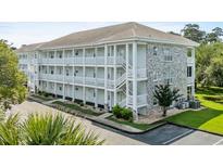 Three-story condo building featuring white balconies, stairs, and a decorative stone facade at 4655 Wild Iris Dr. # 41-303, Myrtle Beach, SC 29577