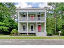 Charming two-story home featuring a double porch, a pink front door, and lush green landscaping at 55 Pineberry Dr., Georgetown, SC 29440