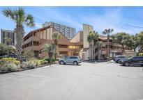 Coastal condo building with palm trees, ample parking, and tan wood siding at 5505 N Ocean Blvd. # 303, Myrtle Beach, SC 29577
