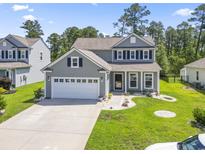 Charming two-story home featuring gray siding, a two-car garage, and a well-manicured front yard with green grass at 597 Heritage Downs Dr., Conway, SC 29526
