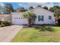 Charming home featuring an attached garage, a manicured lawn, and a small palm tree in the front yard at 628 Lake Estates Ct., Conway, SC 29526