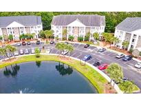 Condominium complex featuring lush landscaping with a large pond and ample parking for residents and guests at 118 Birch N Coppice Dr. # 6, Surfside Beach, SC 29575