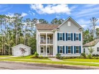 Charming two-story home featuring a double porch, gray siding, blue shutters, and a detached two-car garage at 1216 Newell Dr, Myrtle Beach, SC 29588