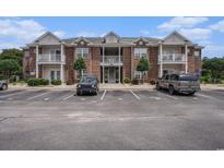 Brick condo building featuring a second-story porch, assigned parking spaces, and manicured landscaping at 2005 Silvercrest Dr. # 32F, Myrtle Beach, SC 29579