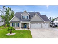 Charming two-story home featuring a three-car garage, well-manicured lawn, and inviting front porch at 2554 Dogwood Rd., Longs, SC 29568