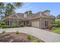 Brick home featuring a paver driveway, manicured landscaping, and a two-car garage at 280 Oatland Lake Rd., Pawleys Island, SC 29585