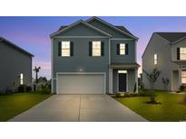 Charming two-story home featuring a two-car garage, blue siding, and well-maintained landscaping at 3657 Bells Lake Circle, Longs, SC 29568