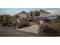 Unique round home with a brick and white exterior, palm trees, and a welcoming driveway at 4552 River Rd., Little River, SC 29566